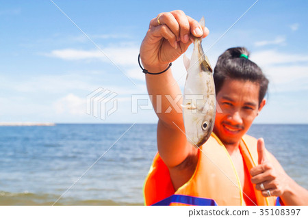 Asian man in life jacket holding died fish Asian man in life jacket holding died fish 35108397
