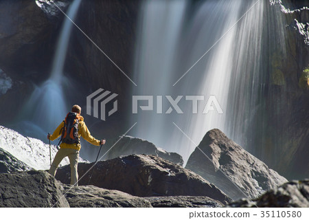 Hiking man with backpack looking at waterfall 35110580