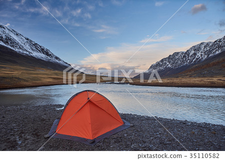 An orange tent near a river in the Mountains 35110582