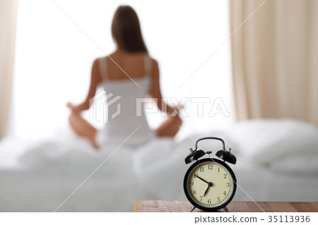 Alarm clock standing on bedside table has already 35113936