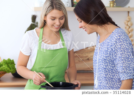 Two young happy woman making cooking in the 35114028