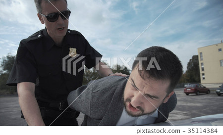 Policeman arresting criminal on parking lot 35114384