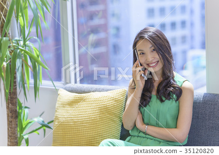 一個美麗的美麗的女人與長發的喵喵誰通過坐在陽光舒適的窗戶的沙發上操作智能手機犯了一個錯誤 35120820