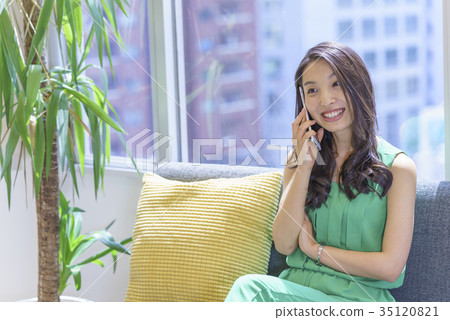 一個美麗的美麗的女人與長發的喵喵誰通過坐在陽光舒適的窗戶的沙發上操作智能手機犯了一個錯誤 35120821