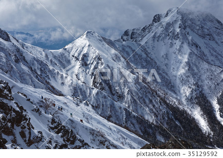 Mountain climber climbs Mt. Amida and Jizozuru seen from Yatsugatake mountain range, Akadake ridge line 35129592