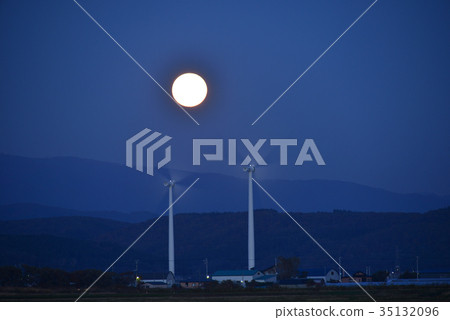 Photographing a twilight wind-powered wind turbine against the full moon that began to climb from the mountains 35132096