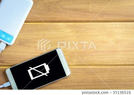 top view charge the smartphone on a wooden table. top view charge the smartphone on a wooden table. 35136528