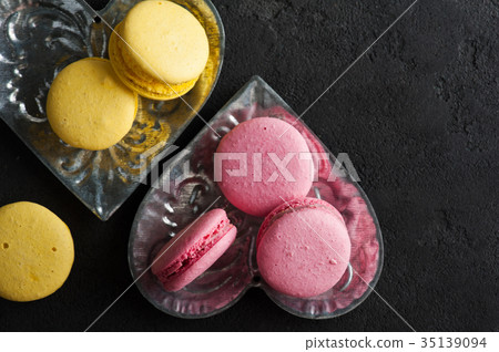 Closeup of yellow pink macaroons on black concrete 35139094