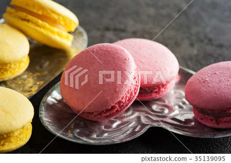 Closeup of yellow pink macaroons on black concrete Closeup of yellow pink macaroons on black concrete 35139095