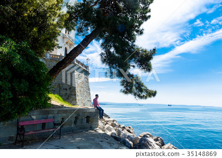 Man sits near the Miramare castle in Italy 35148869