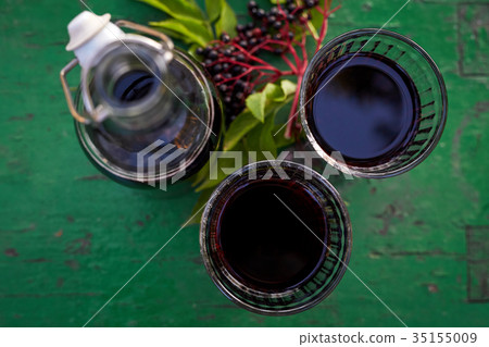 Glasses of fresh elderberry syrup and elderberries 35155009