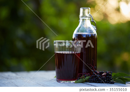 Glass of fresh elderberry syrup and elderberries 35155010