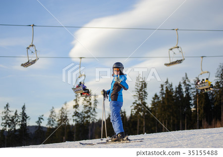 Female skier against ski-lift and forest on a sunny day Female skier against ski-lift and forest on a sunny day 35155488