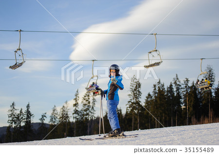 Female skier against ski-lift and forest on a sunny day Female skier against ski-lift and forest on a sunny day 35155489