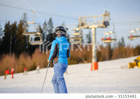 Female skier against ski-lift and forest on a sunny day 35155491