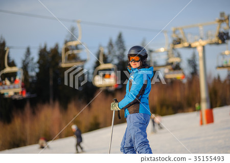 Female skier against ski-lift and forest on a sunny day 35155493