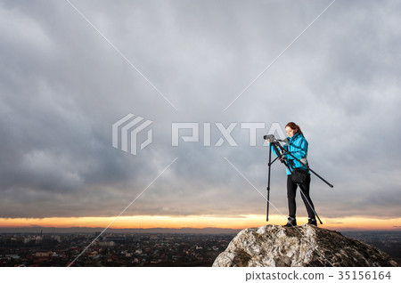 Female photographer with camera on tripod on the big rock 35156164