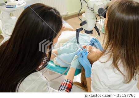 Female dentist treating caries using microscope at the dentist office Female dentist treating caries using microscope at the dentist office 35157765