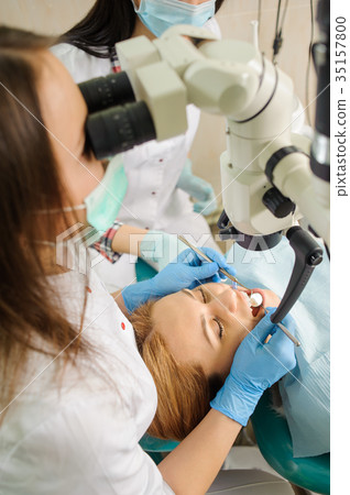 Female dentist treating caries using microscope at the dentist office Female dentist treating caries using microscope at the dentist office 35157800