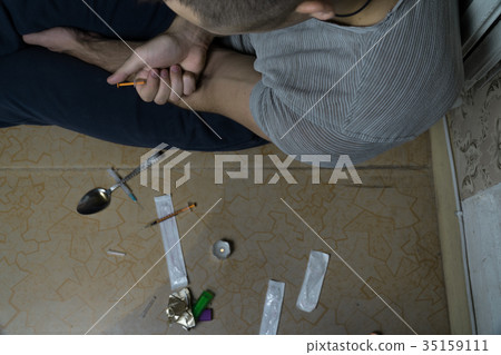 The guy who is addicted to drugs, sits on  floor 35159111