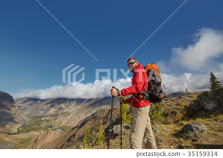 Handsome young male hiker sitting on the edge of a 35159314