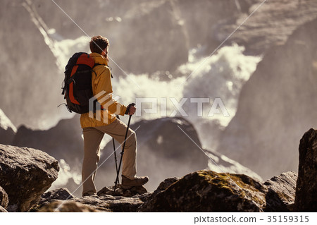 Hiker hiking with backpack looking at waterfall 35159315