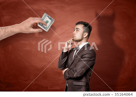 A giant hand with a roll of dollar bills in front A giant hand with a roll of dollar bills in front 35164064