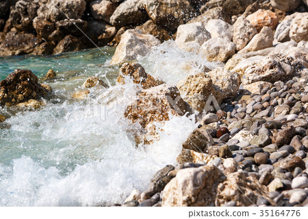 waves break against the rocks  35164776