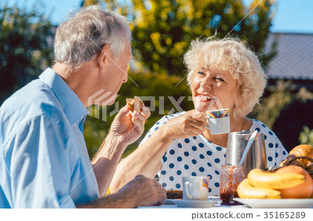 Happy elderly couple eating breakfast in their Happy elderly couple eating breakfast in their 35165289