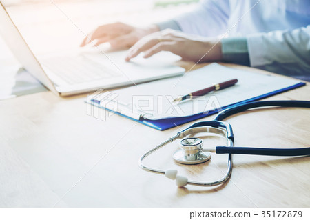 Doctor typing information on Laptop in Hospital  35172879