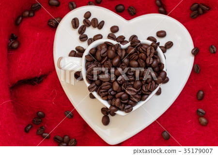 Heart shaped cup with coffee beans on red Heart shaped cup with coffee beans on red 35179007