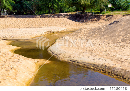Sand beach pollution. Black water in creek on sand Sand beach pollution. Black water in creek on sand 35180438