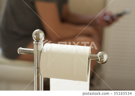 young man using his smartphone in the toilet 35183534