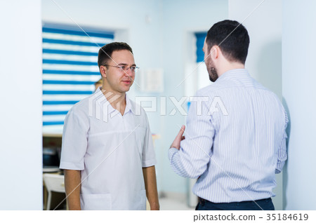 Doctor talking to a patient in a hallway Doctor talking to a patient in a hallway 35184619
