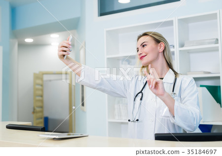 Smiling nurse taking selfies with her phone behind 35184697