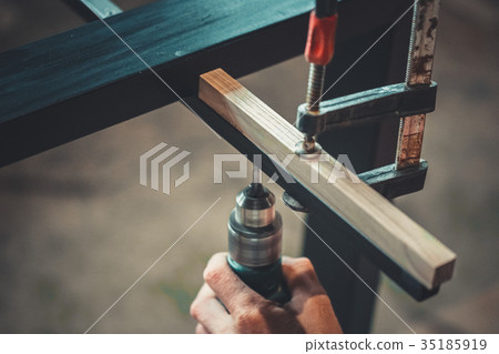 Man using the drill makes a hole in wood and iron Man using the drill makes a hole in wood and iron 35185919