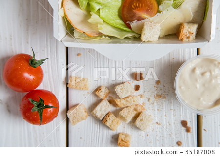 Caesar salad in box on white wooden surface Caesar salad in box on white wooden surface 35187008