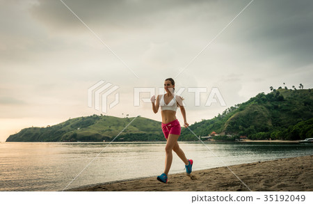 Fit young woman running on the beach during summer 35192049