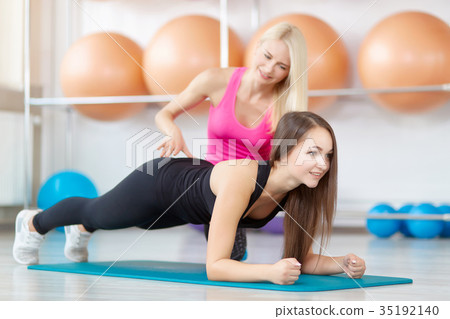 Young woman exercising with her fitness instructor 35192140