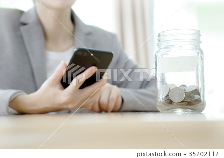 Businesswoman hid behind a jar full of coins Businesswoman hid behind a jar full of coins 35202112