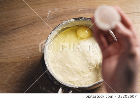 adding egg into saucepan with dough adding egg into saucepan with dough 35208607