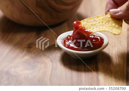 young female hand dipping nachos in tomato salsa 35208700