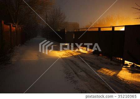 Snow covered suburban road lit by yellow lights at Snow covered suburban road lit by yellow lights at 35210365