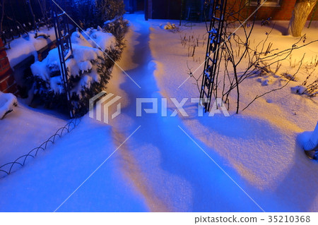 Snow covered path lit by street lights at night Snow covered path lit by street lights at night 35210368