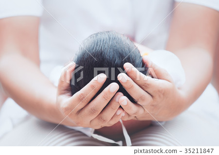 Mother holding head of her newborn baby in hands 35211847
