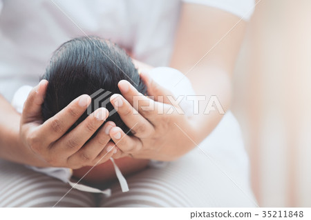 Mother holding head of her newborn baby in hands Mother holding head of her newborn baby in hands 35211848