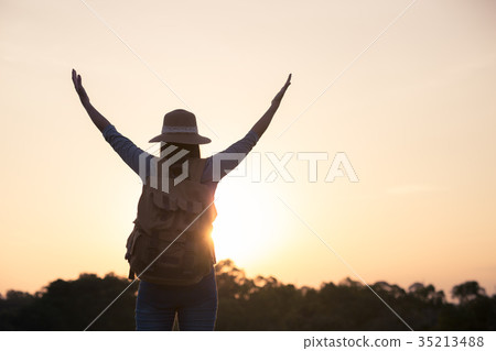 Women raise their hands at sunset in warm light Women raise their hands at sunset in warm light 35213488