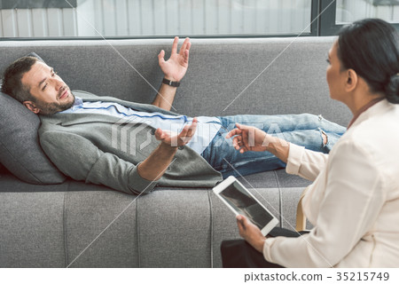 Bewildered man visiting female psychologist 35215749