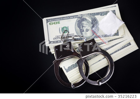 Handcuffs on stack of dollar banknotes and cocaine Handcuffs on stack of dollar banknotes and cocaine 35216223