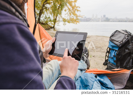 Man using digital tablet in camping tent Man using digital tablet in camping tent 35216531